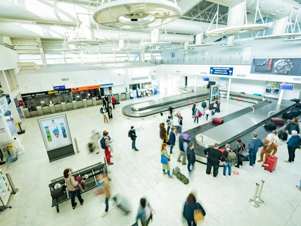 Photo prise de haut des tapis de bagages avec les gens attendant leurs bagages