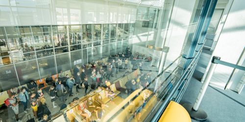 Vue de l'intérieur en hauteur de l'aérogare avec les voyageurs qui patientent